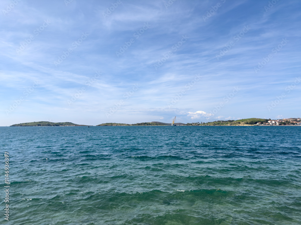 A serene view of the Aegean Sea near Izmir, featuring clear turquoise and blue-green waters under a bright sky. The natural beauty of the coast captures the essence of summer tranquility A serene view of the Aegean Sea near Izmir, featuring clear turquoise and blue-green waters under a bright sky. The natural beauty of the coast captures the essence of summer tranquility