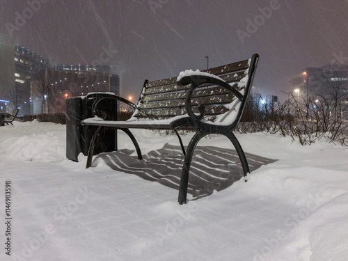 Cast iron bench standing in the park during snowfall. photo