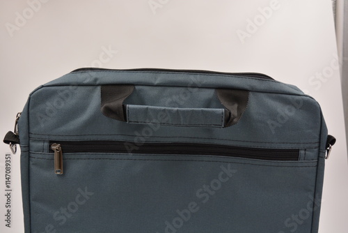 Casual items, equipment, green, gray soft laptop bag with black metal zippers is located on a black plastic background. photo