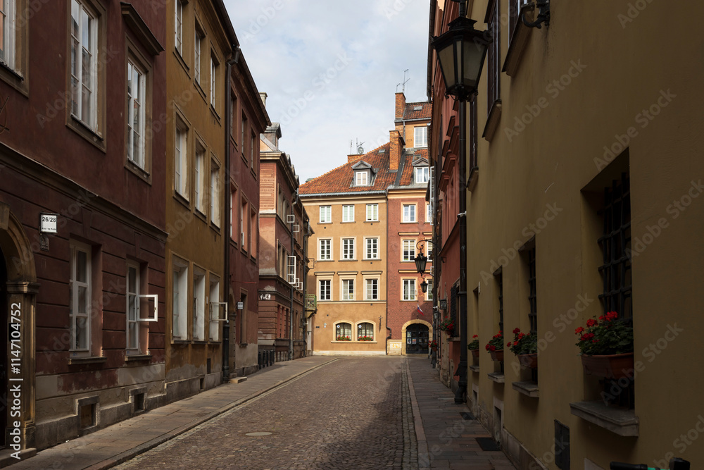 Warsaw, Poland - September 2, 2024, Houses and streets of the Old Town, the road is paved with cobblestones. Windowsills are decorated with flowerpots containing blooming geraniums. Warsaw, Poland - September 2, 2024, Houses and streets of the Old Town, the road is paved with cobblestones. Windowsills are decorated with flowerpots containing blooming geraniums.