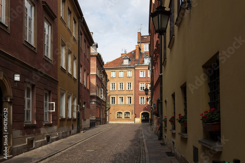 Warsaw, Poland - September 2, 2024, Houses and streets of the Old Town, the road is paved with cobblestones. Windowsills are decorated with flowerpots containing blooming geraniums.