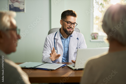 Happy male doctor talking with his patients while having an appointment in the office.