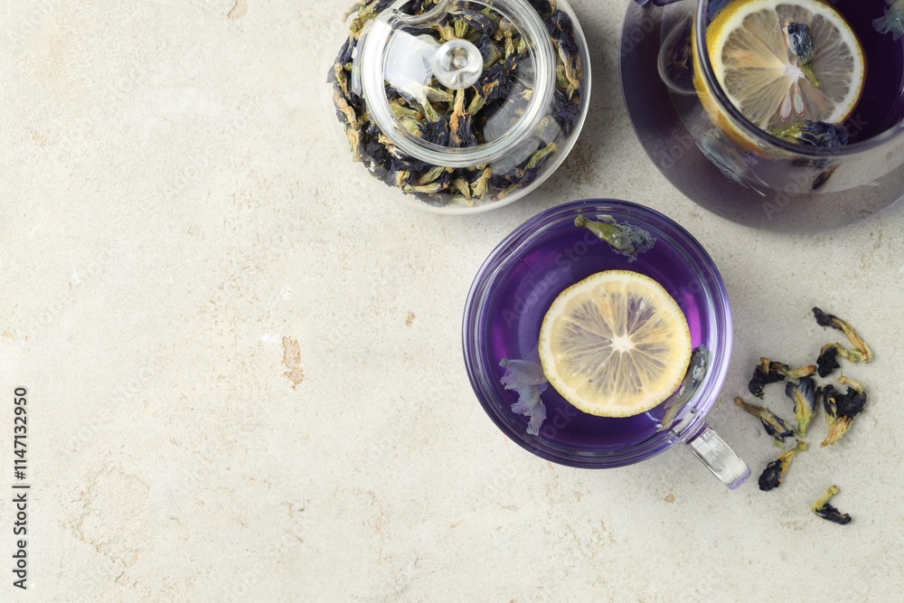 Delicious butterfly pea flower tea with lemon on gray textured table, flat lay. Space for text Delicious butterfly pea flower tea with lemon on gray textured table, flat lay. Space for text