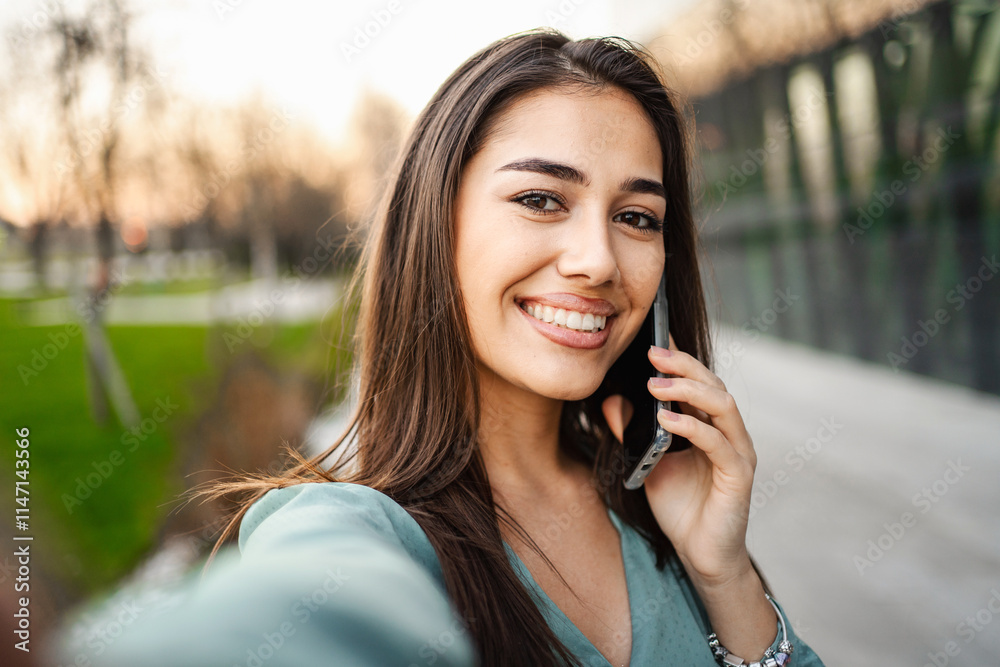 Selfie of smiling young brunette girl using mobile phone outdoors Selfie of smiling young brunette girl using mobile phone outdoors