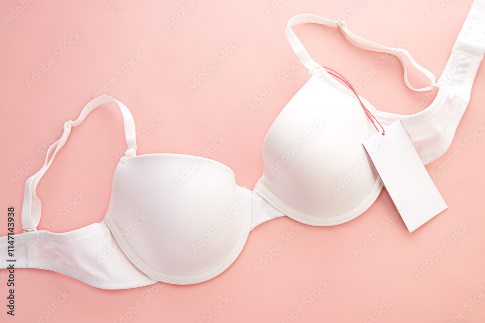 White women's bra with white paper label on pink background White women's bra with white paper label on pink background