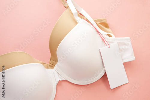 Women's bras with white paper labels on pink background