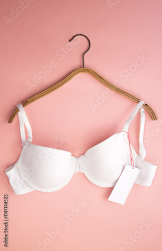 White women's bra with white paper label on pink background