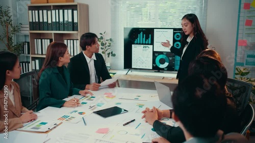 Business team analyzing financial data and company's performance during a meeting in the office, a businesswoman leads the presentation showing charts and graphs on a monitor