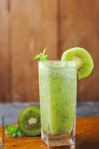 a glass of kiwi fruit juice, on a wooden background