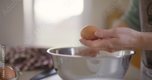 Woman cracks raw egg into bowl and prepares dough
