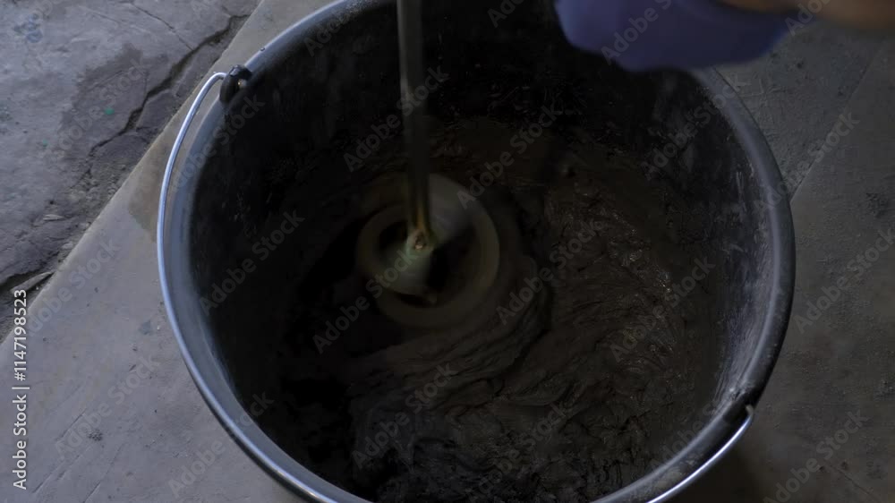 Electric mixer broke down while preparing wall adhesive mixture in bucket for home renovation. Malfunction halted construction or home repair process. Mixing building adhesive liquid for wall tiling Electric mixer broke down while preparing wall adhesive mixture in bucket for home renovation. Malfunction halted construction or home repair process. Mixing building adhesive liquid for wall tiling