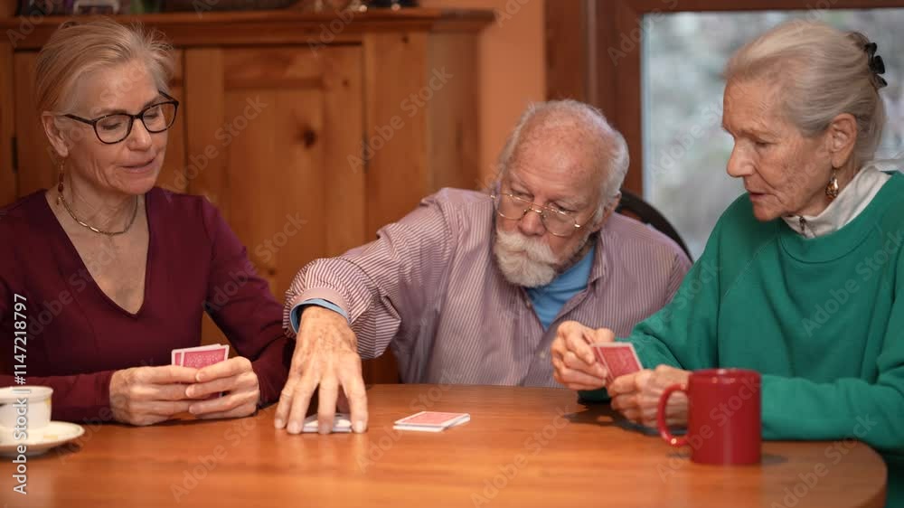 Family members gather around a wooden table playing cards and sharing laughter in a cozy living room. The elderly couple relishes quality time with their daughter. Family members gather around a wooden table playing cards and sharing laughter in a cozy living room. The elderly couple relishes quality time with their daughter.