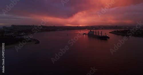 Coal Ship leaving Newcastle Harbour during sunset after storm with purple, orange sky