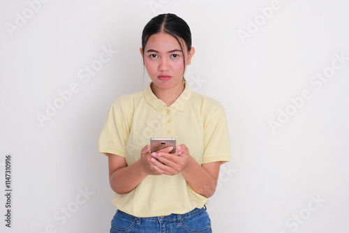 A woman with sad expression while holding her mobile phone photo