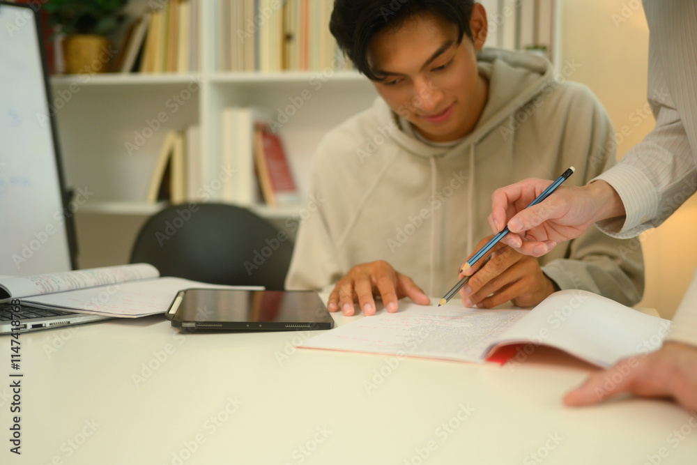 Fototapeta premium Tutor pointing to important sections in a notebook assisting a student during a study session