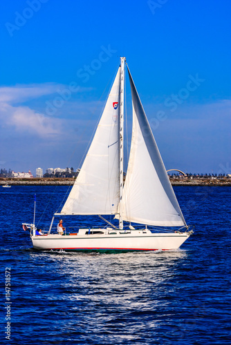 A sailboat is sailing in the ocean with a blue sky in the background