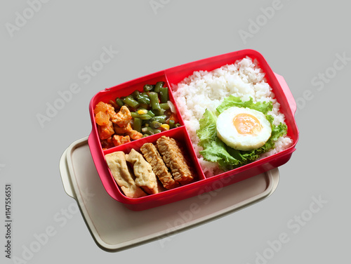 A balanced, healthy meal of rice, egg, stir-fried vegetables, and tofu-tempeh, in a lunchbox, suits busy students and office workers. A free lunch program by Prabowo in Indonesia served in a lunchbox. photo