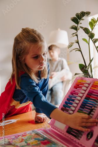 Young girl in superhero costume picking a colouring texta photo