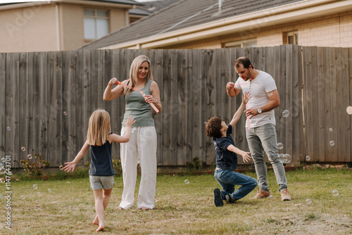 Happy family blowing and playing with bubbles in their yard. photo