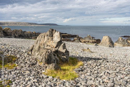 Pebble and sharp-edged rocks by the Barents Sea on a sunny summer afternoon just outside the village of Hamninberg. Finnmark, Northern Norway photo