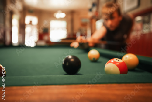 Teenage male playing 8 ball pool on billiard table in Australian pub