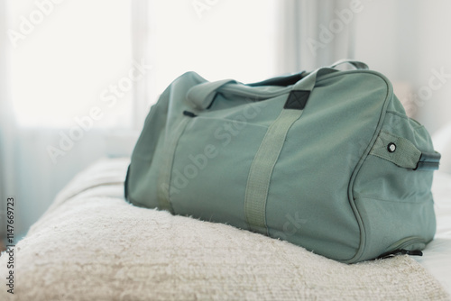 Green travel bag on a neatly made bed in bright, cozy bedroom photo