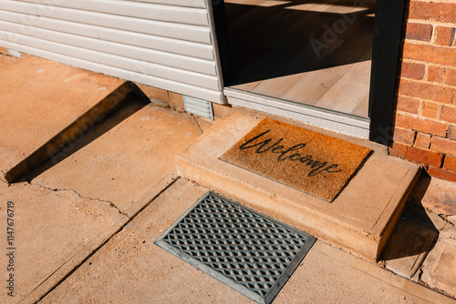 Welcome doormat at house entrance with warm message on a sunny day photo