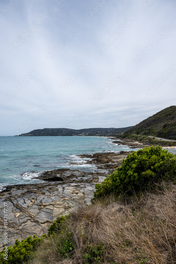 Great Ocean Road scenery with ocean coming to rocky shore under overcast sky Great Ocean Road scenery with ocean coming to rocky shore under overcast sky
