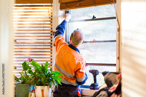 Handyman tradie repairing window in home photo