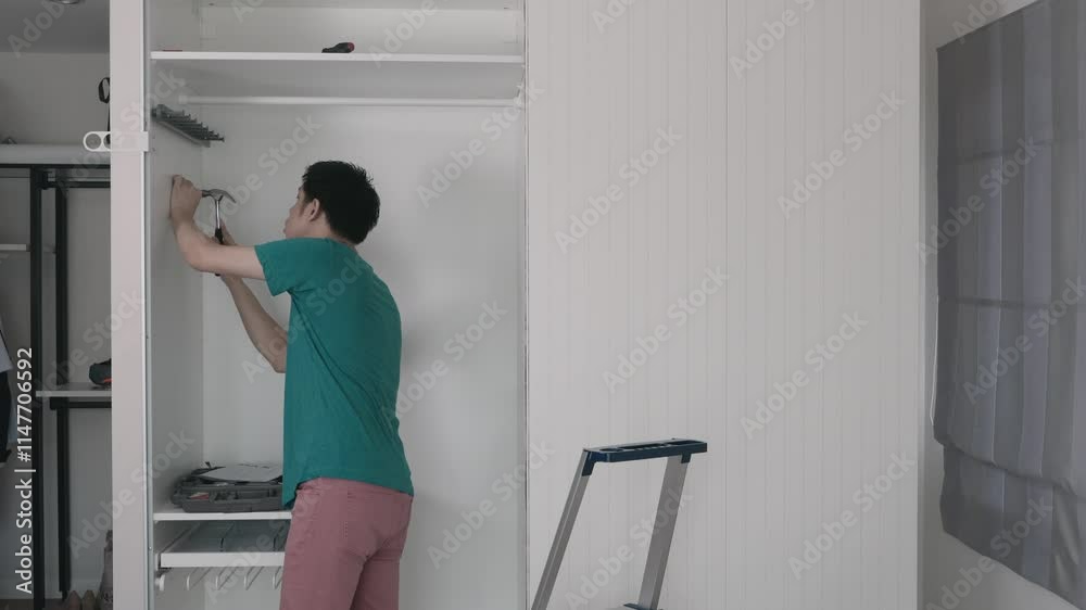 A man is opening a cabinet door. The man is wearing a green shirt A man is opening a cabinet door. The man is wearing a green shirt
