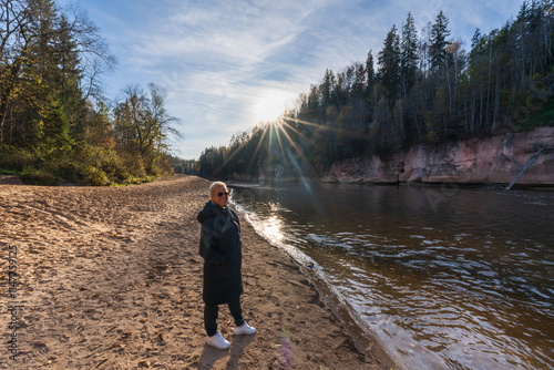 Romantic walk of a girl along the river in the rays of the setting sun. Latvian autumn. photo