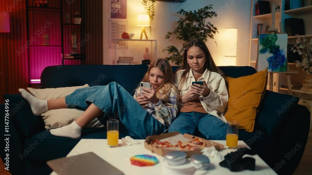 Teens use phones on the couch, ignoring each other, gadget addiction concept