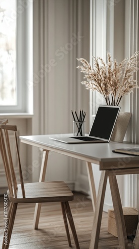 Minimalist home office workspace with laptop, chair, and pampas grass.