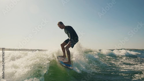 A wakeboarder performs exciting tricks on his board, moving quickly through the water. The footage shows smooth turns, jumps and acrobatics, highlighting the athlete's skill and endurance. Ideal for t