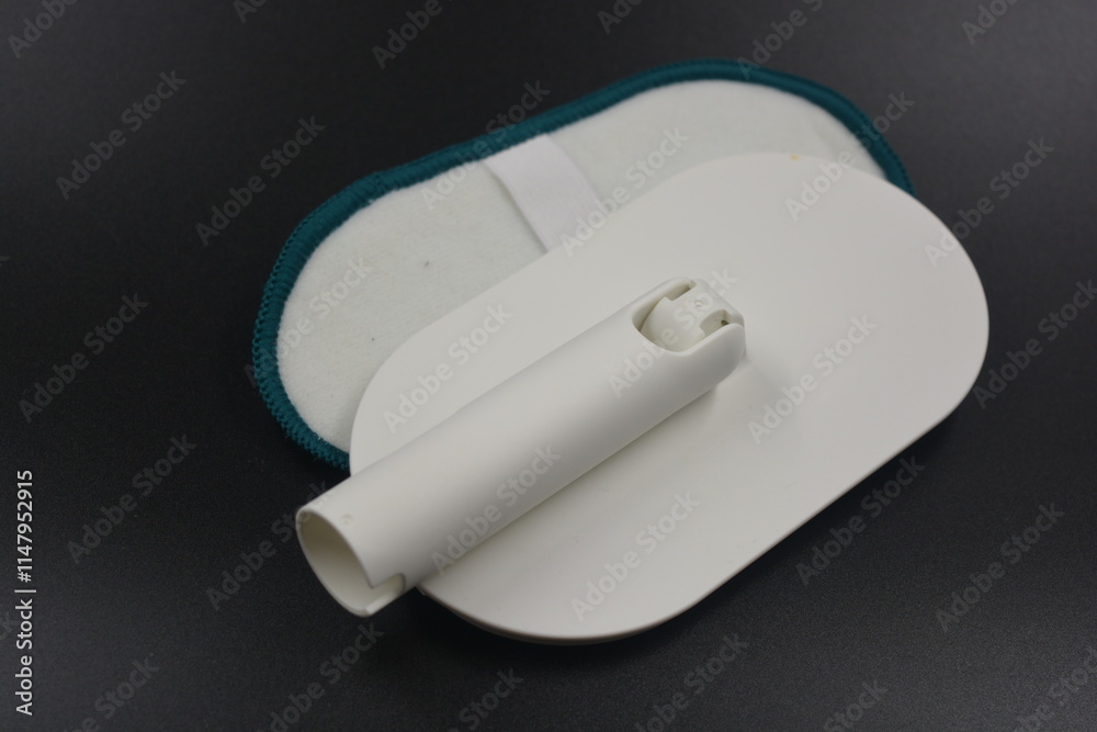 Plastic white tool with green microfiber, cloth. An object for washing and cleaning windows, glass located on a black, matte plastic background. Plastic white tool with green microfiber, cloth. An object for washing and cleaning windows, glass located on a black, matte plastic background.