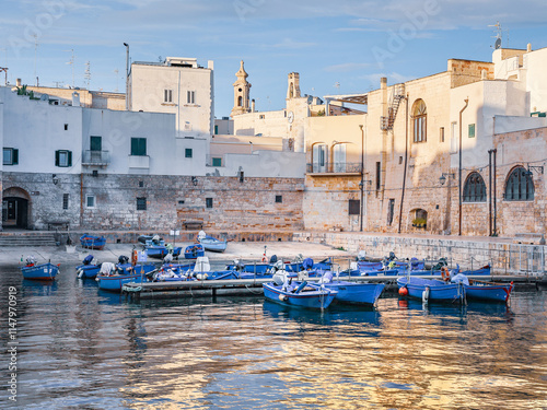 Obraz na plátně Ancient mediterranean town on seaside with vivid blue fishing boats in old harbo