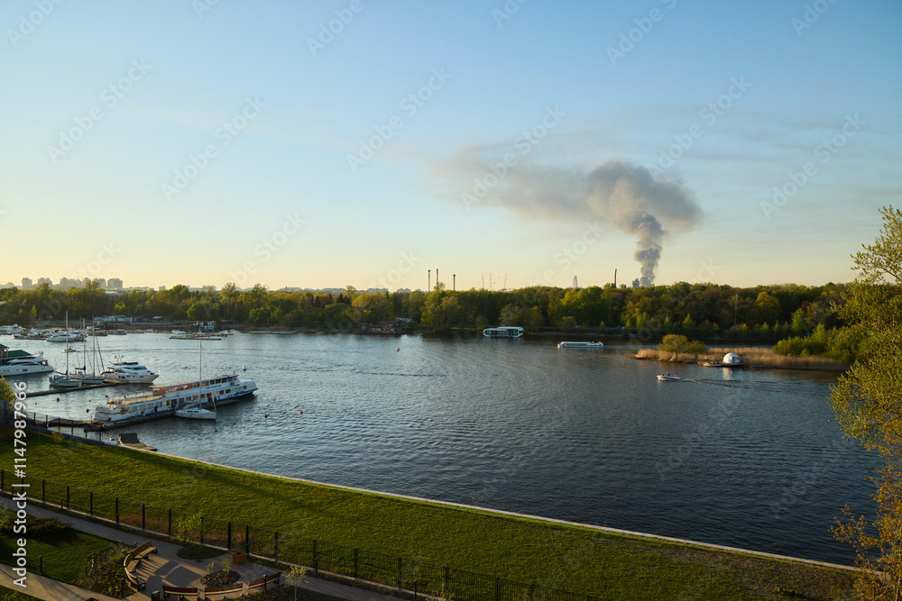 Naklejka premium A picturesque river view featuring smoke in the background during the beautiful dusk