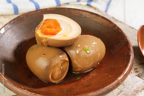 Ajitama eggs, Japanese-style marinated soft-boiled eggs, served in a rustic brown bowl. The golden yolk and soy-infused flavor make this dish perfect for ramen, rice bowls, or as a standalone snack. photo