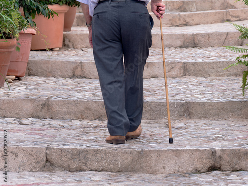 Elderly man walking with cane on stone steps