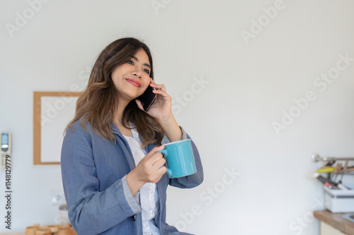 Young Freelance Woman Working from Home, Talking on Phone in Dining Room, Holding Coffee Mug, Remote Work Concept photo