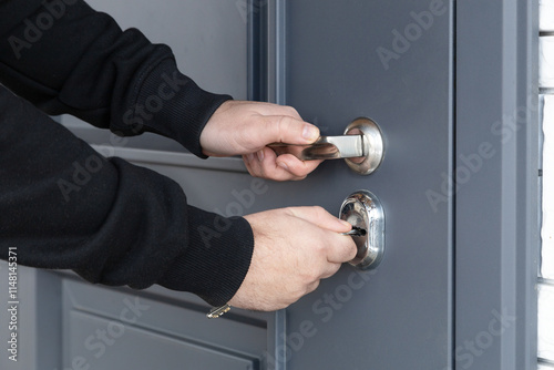 Man opens the lock of the front door of a private house. Keys, hands, keyhole close-up. Concept of security, theft, burglary, preservation of property..