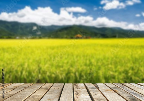 Wooden table top on blur rice field and mountain background in daytime.Harvest rice or whole wheat.For montage product display or design key visual layout.View of copy space. photo