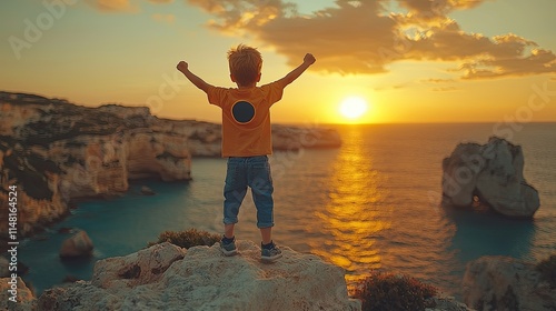 A child stands triumphantly on a cliff, watching a beautiful sunset over the ocean.