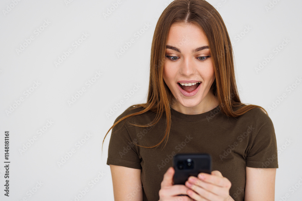 Young shocked young woman posing isolated over white wall background using mobile phone. Young shocked young woman posing isolated over white wall background using mobile phone.
