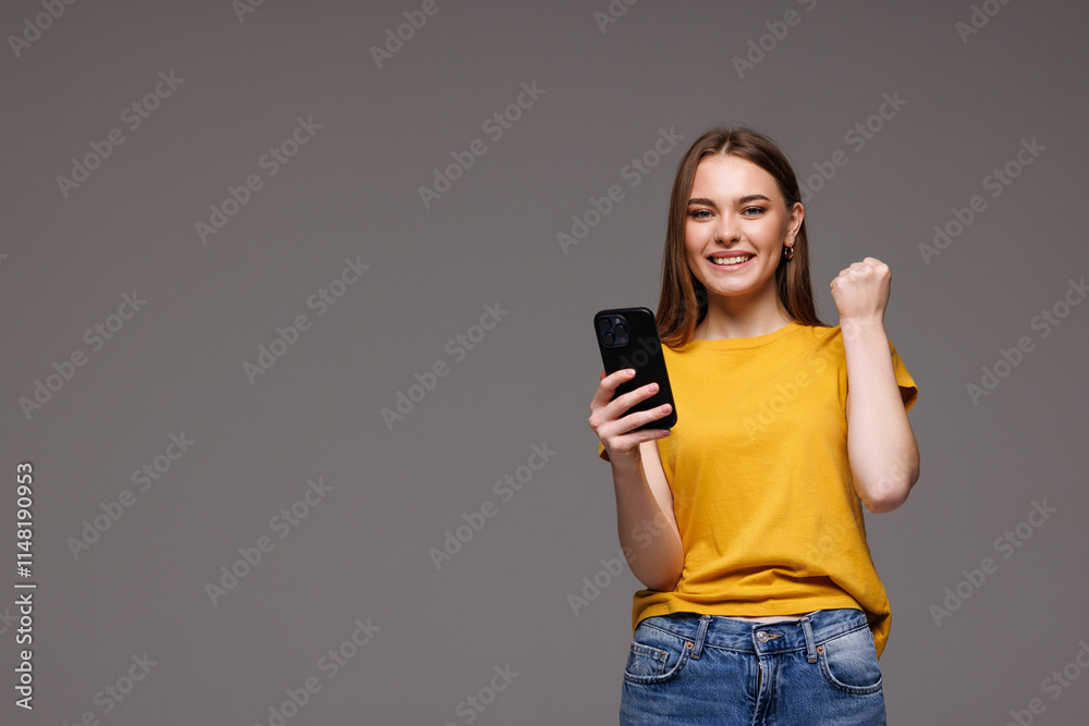 Satisfied excited woman with modern phone device in hand isolated on grey background Satisfied excited woman with modern phone device in hand isolated on grey background
