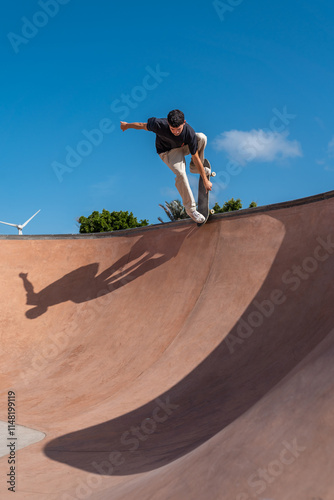 young skater wearing black tshirt skating inside a bowl in a skate park. 