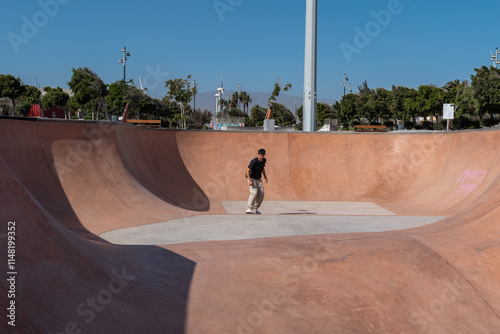 young skater wearing black tshirt skating inside a bowl in a skate park.  photo