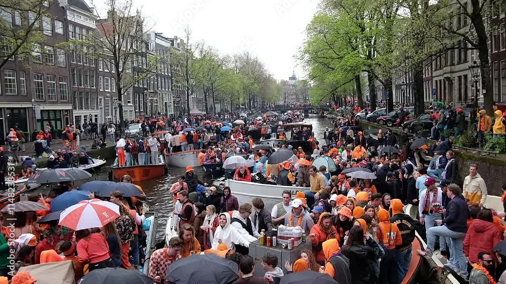 Amsterdam, Netherlands - April 27, 2024: Locals celebrating Kingsday in Amsterdam on the canals in the Netherlands