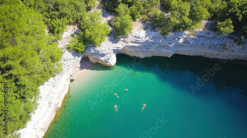 Forests and Swimming, Aerial view of a serene cove with turquoise water, surrounded by lush greenery and rocky cliffs, featuring people swimming.