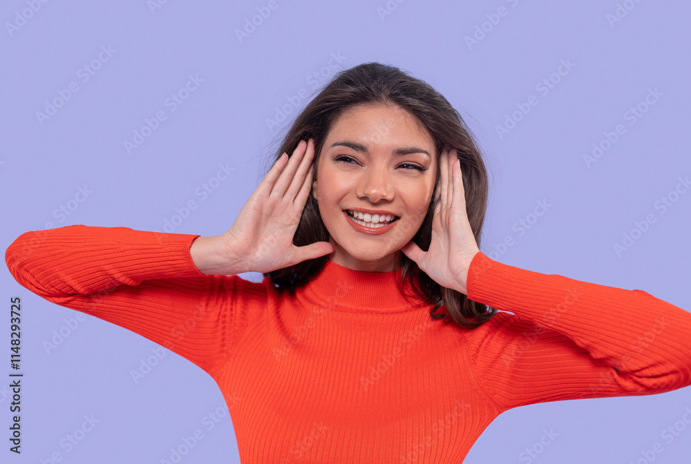 Smiling woman in bright orange sweater conveys happiness against a lilac background Smiling woman in bright orange sweater conveys happiness against a lilac background